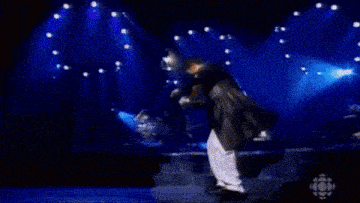 a man in a black jacket is playing a violin on a stage .