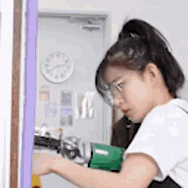 a woman is working on a machine in a room with a clock on the wall .