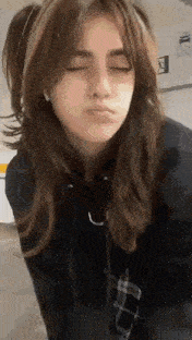 the girl is wearing a black hoodie and making a face .