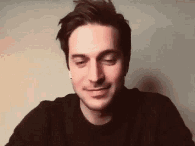 a man wearing ear buds is smiling while sitting at a table .