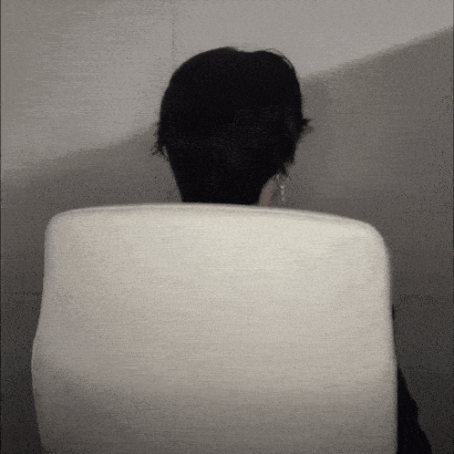 a person sitting in a white chair with their head behind the back