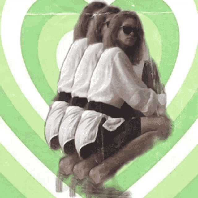 a woman wearing sunglasses is sitting in front of a green heart