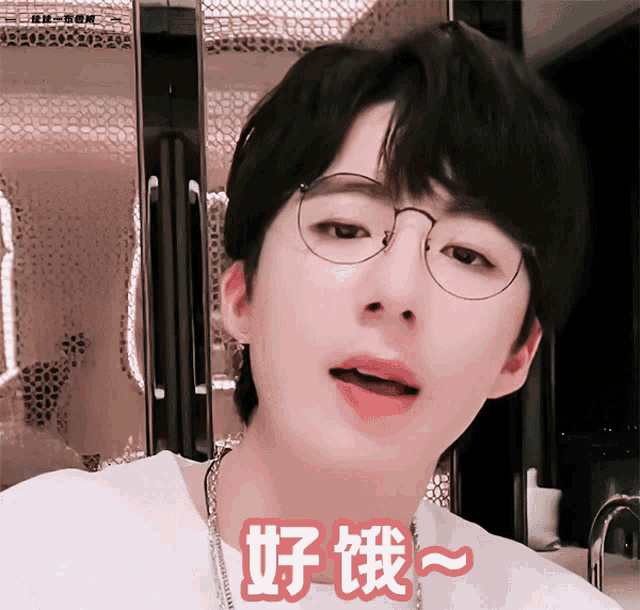 a young man wearing glasses and a white shirt has chinese characters on his face