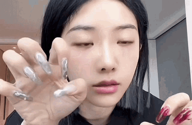 a close up of a woman 's face with her eyes closed and her nails painted .