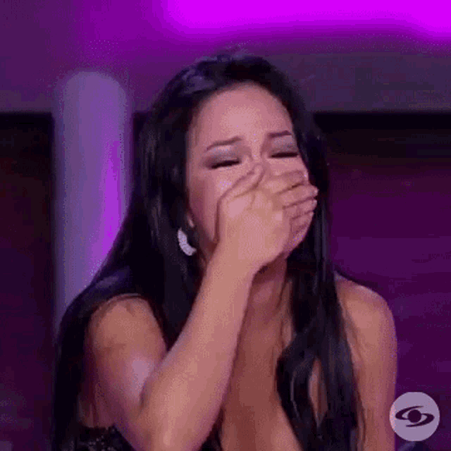 a woman is crying and covering her mouth with her hands .