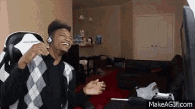 a man wearing headphones is sitting in a chair laughing .