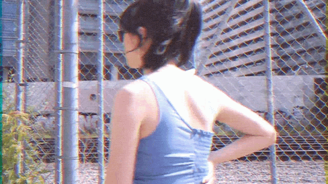 a woman standing in front of a chain link fence