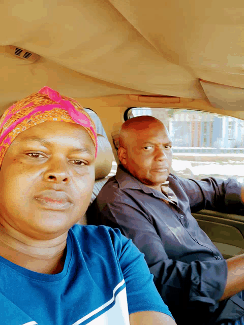 a man and a woman are sitting in a car and the woman is wearing a pink headband