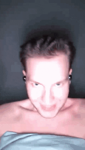 a man without a shirt is making a funny face while wearing headphones .