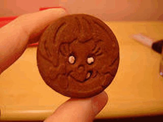 a close up of a person holding a cookie with a face carved into it