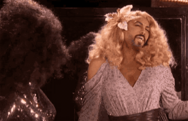 a man in a wig with a flower in his hair is standing next to another man