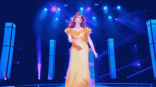 a woman in a yellow dress is standing on a stage in front of a blue light .