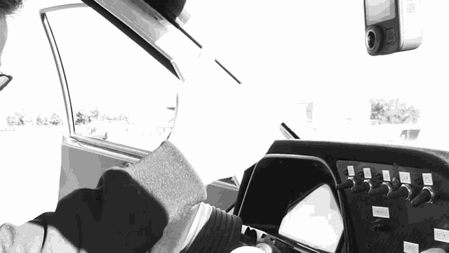 a black and white photo of a person in a car with a dash board that says ' emergency '