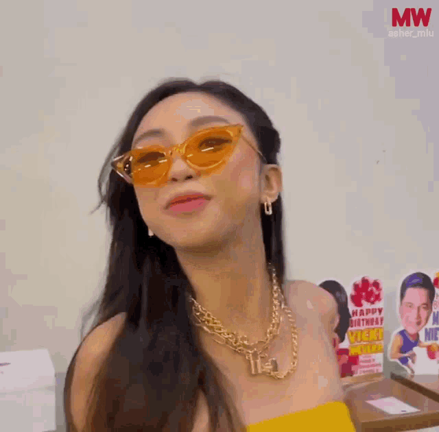 a woman wearing sunglasses and a yellow top is laughing