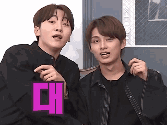 two young men are standing next to each other and one of them has a purple sticker on his shirt that says ' ch '