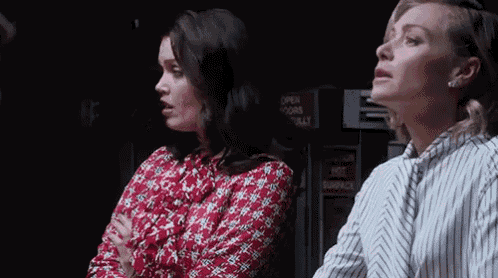 two women are sitting next to each other in a dark room and looking up .