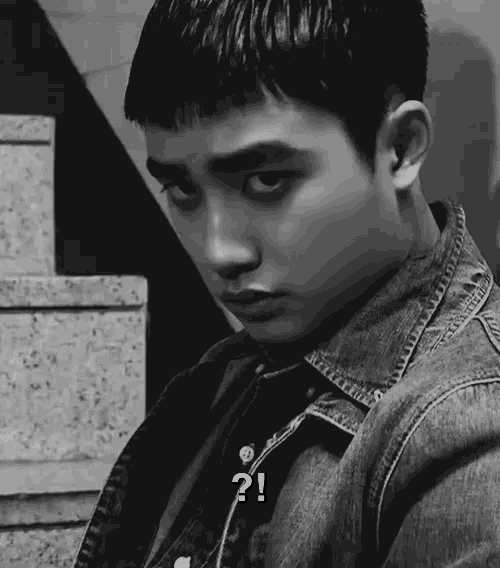 a black and white photo of a young man wearing a denim jacket with a question mark on his face