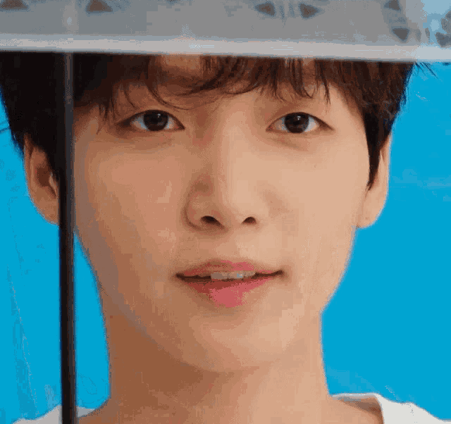 a close up of a young man 's face with an umbrella over his head
