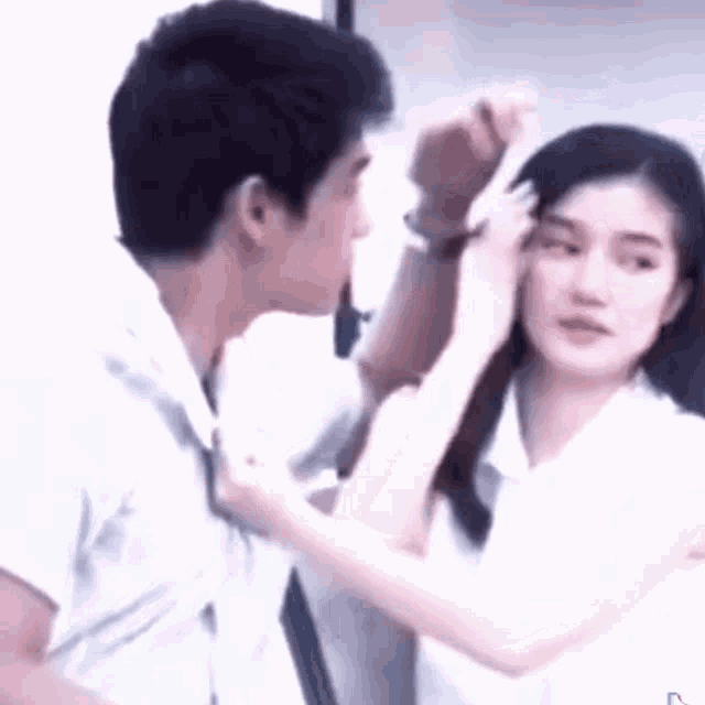 a man and a woman are standing next to each other . the man is touching the woman 's face .