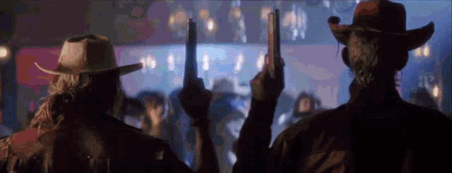 two men in cowboy hats holding up their guns in front of a crowd