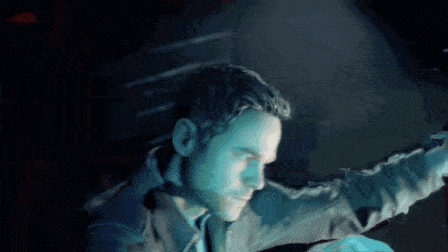 a man is standing in a dark room with a blue light behind him .