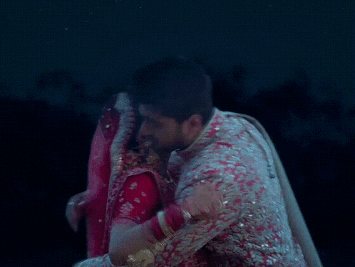 a man and a woman are hugging each other in a dark room