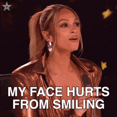a woman is sitting in front of a microphone and says her face hurts from smiling