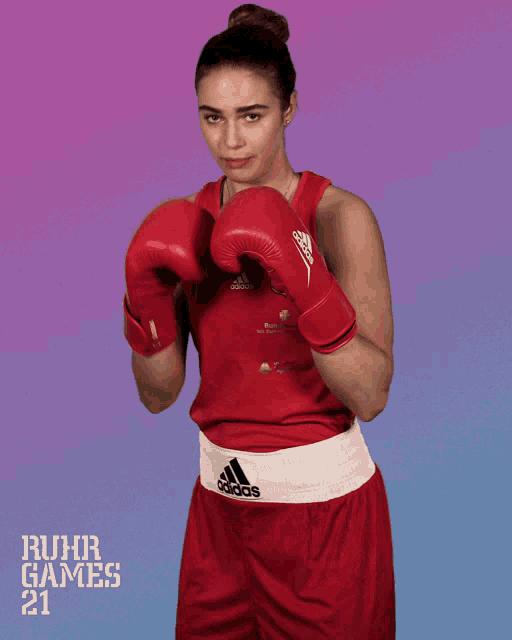 a woman wearing red adidas boxing gloves stands in front of ruhr games 21