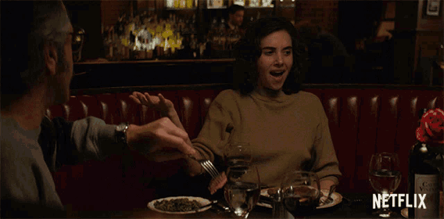 a woman is sitting at a table with a bottle of netflix in the background