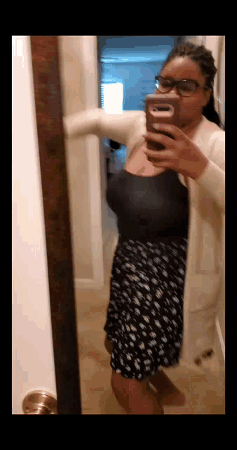 a woman taking a selfie in front of a mirror with her phone