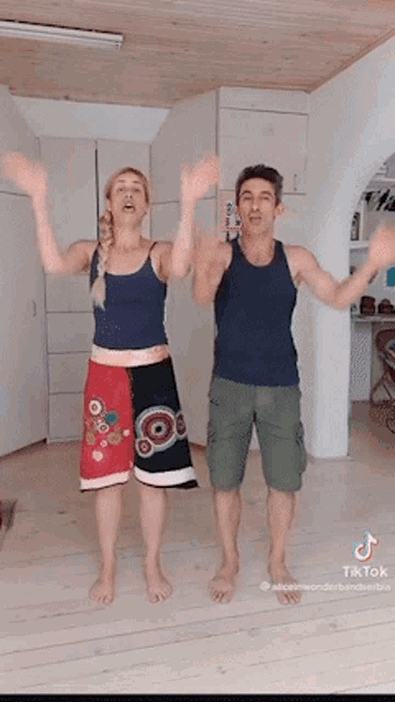 a man and a woman are dancing together in a room with their arms in the air .