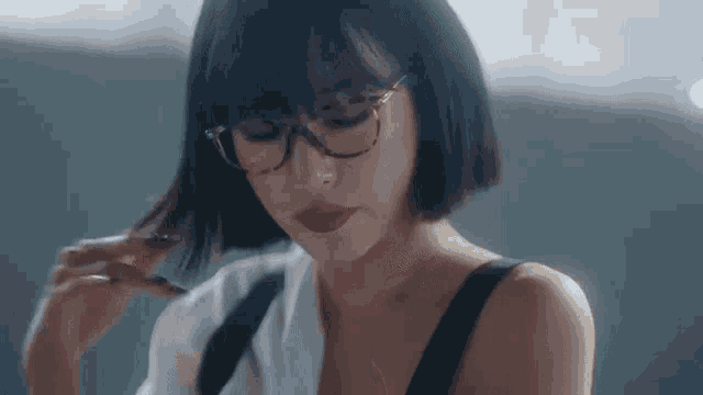 a woman wearing glasses and a white shirt is looking down .