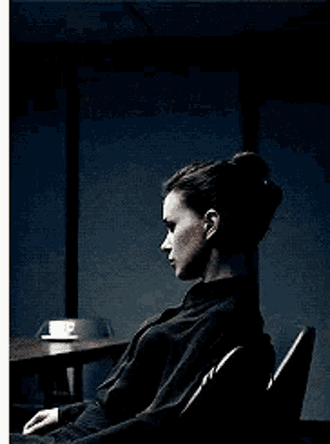 a woman is sitting in a chair with a cup of coffee on the table