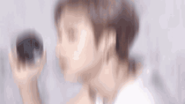 a young man wearing a white shirt and a necklace is holding a black container that says k-beauty on it