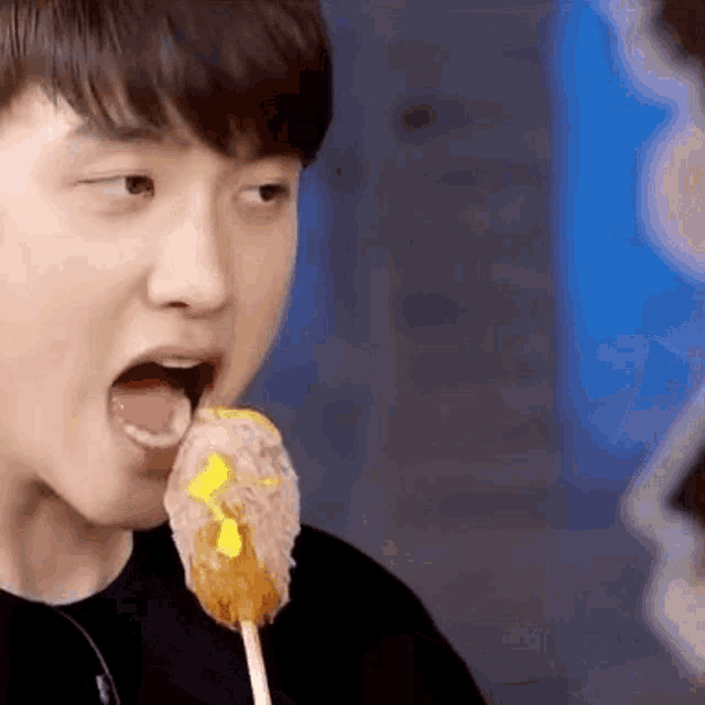 a close up of a person eating a food on a stick .