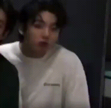 a man in a white shirt is making a funny face while standing next to another man .
