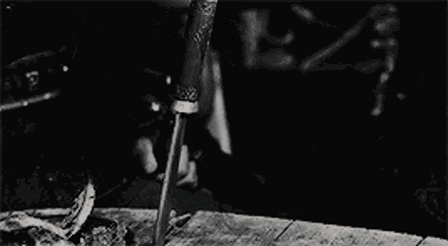 a black and white photo of a person holding a knife on a table