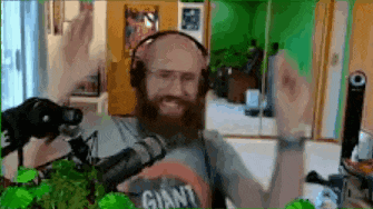 a man with a beard wearing headphones and a shirt that says giant is standing in front of a microphone .