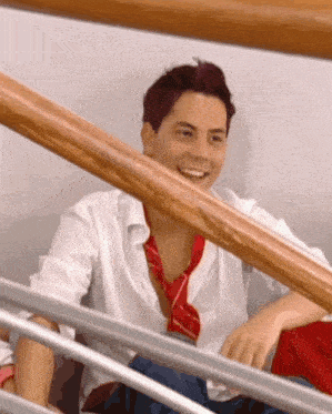 a man wearing a white shirt and red tie is sitting on a staircase