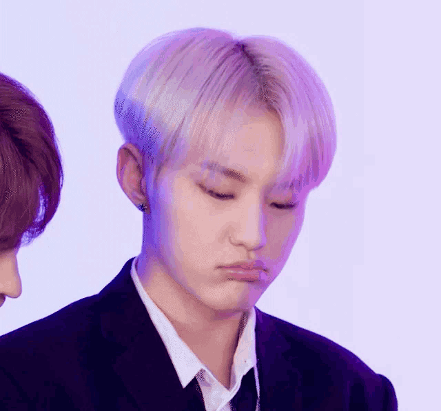 a man in a suit and tie is making a funny face while standing next to another man .