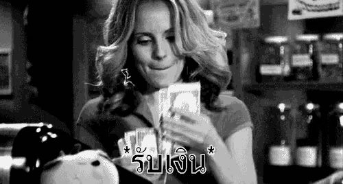a black and white photo of a woman holding a pile of money in front of a piggy bank .