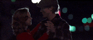 a man in a hat is holding a woman in a red sweater