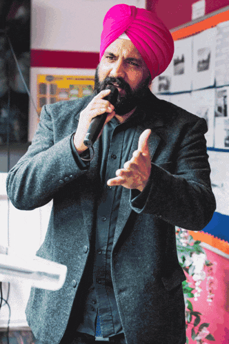 a man in a pink turban is speaking into a microphone
