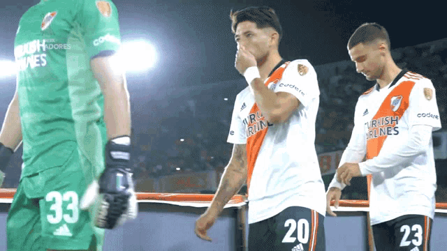a soccer player wearing number 20 wipes his nose