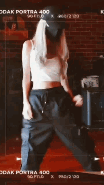 a woman wearing a mask is dancing in front of a kodak camera