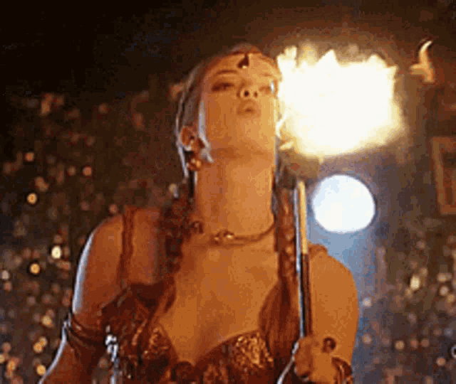 a woman is holding a stick with flames coming out of it 's mouth .