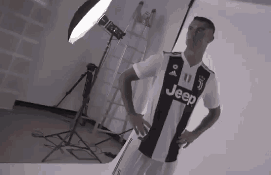 a man in a black and white jeep jersey is standing in front of a light .