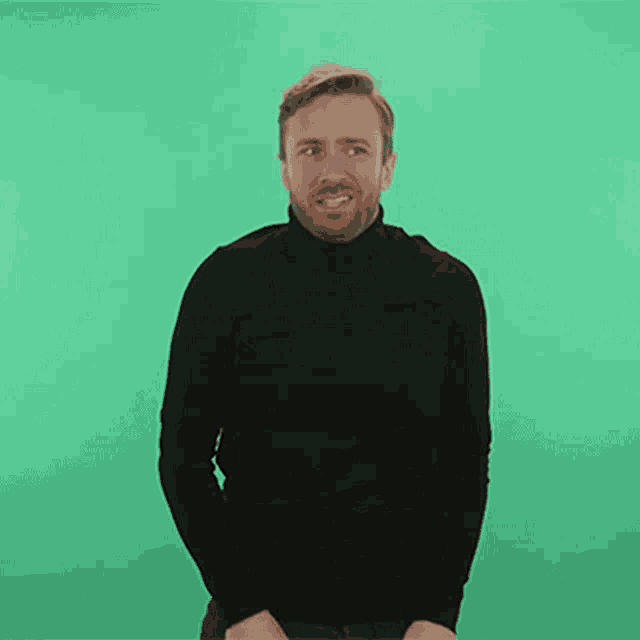 a man with a beard wearing a black turtleneck is smiling