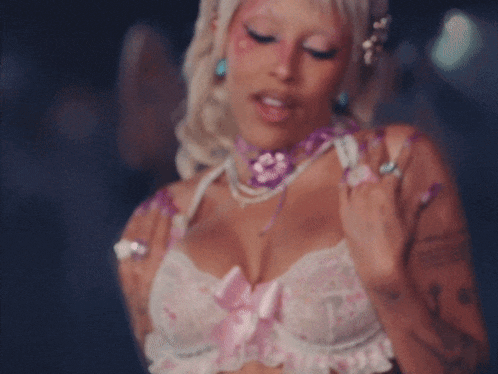a woman is wearing a pink and purple necklace and bra .