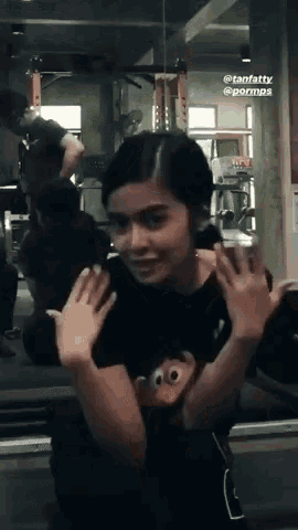 a girl wearing a black shirt with a monkey on it is making a funny face in a gym .